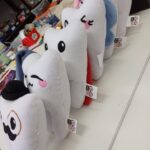 Pluszowe zabawki w kształcie zębów, każda z unikalnym wzorem, ustawione w rządku na stole w pracowni.