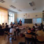 Warsztaty w szkole, podczas których prowadzący omawia temat tworzenia gier miejskich i terenowych.