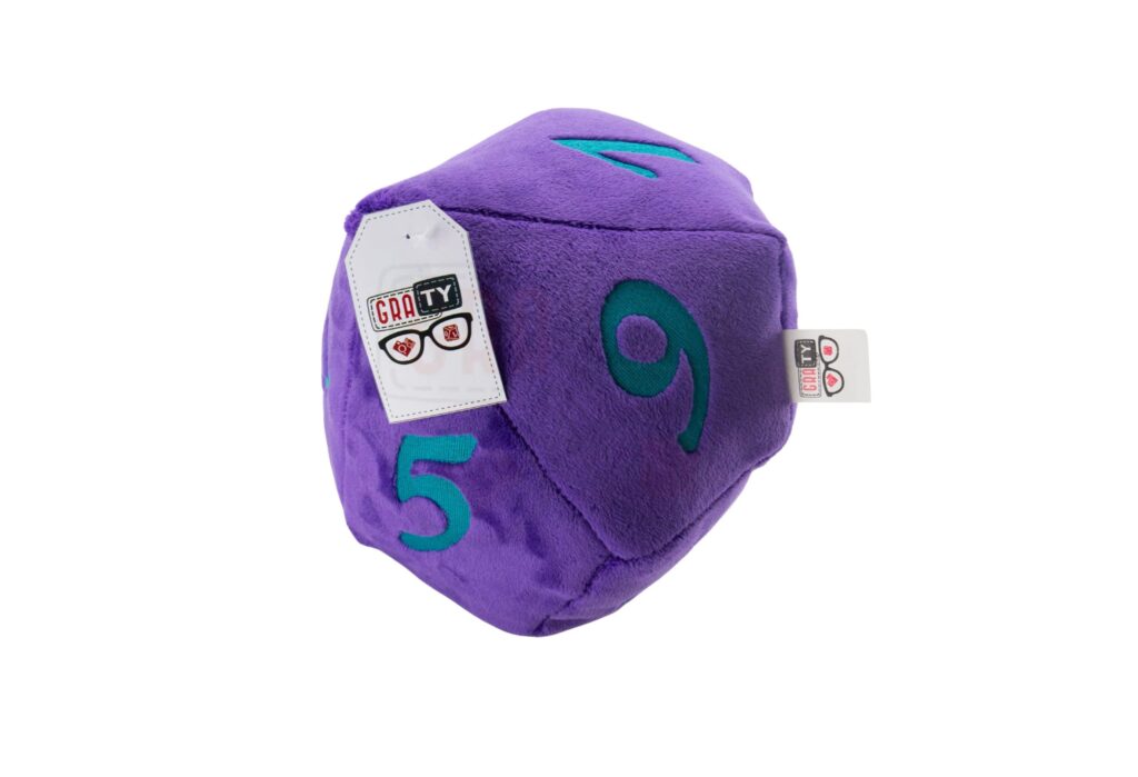 Pluszowa kostka RPG: fioletowa, dziesięciościenna kostka z turkusowymi cyframi 5 i 9, z widocznymi metkami, leżąca na białym tle.