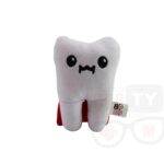 Pluszowy ząb z czerwoną peleryną, leżący na białym tle.